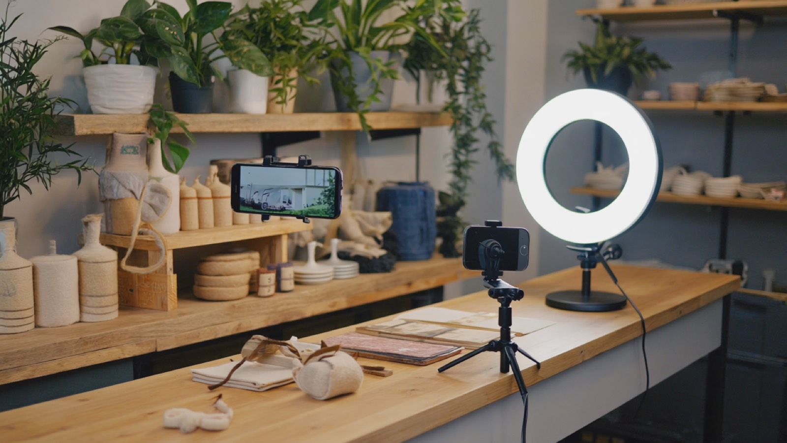 Smartphone auf einem kleinen Stativ, das auf handgemachte Produkte auf einer Ladentheke gerichtet ist, mit Ringlicht